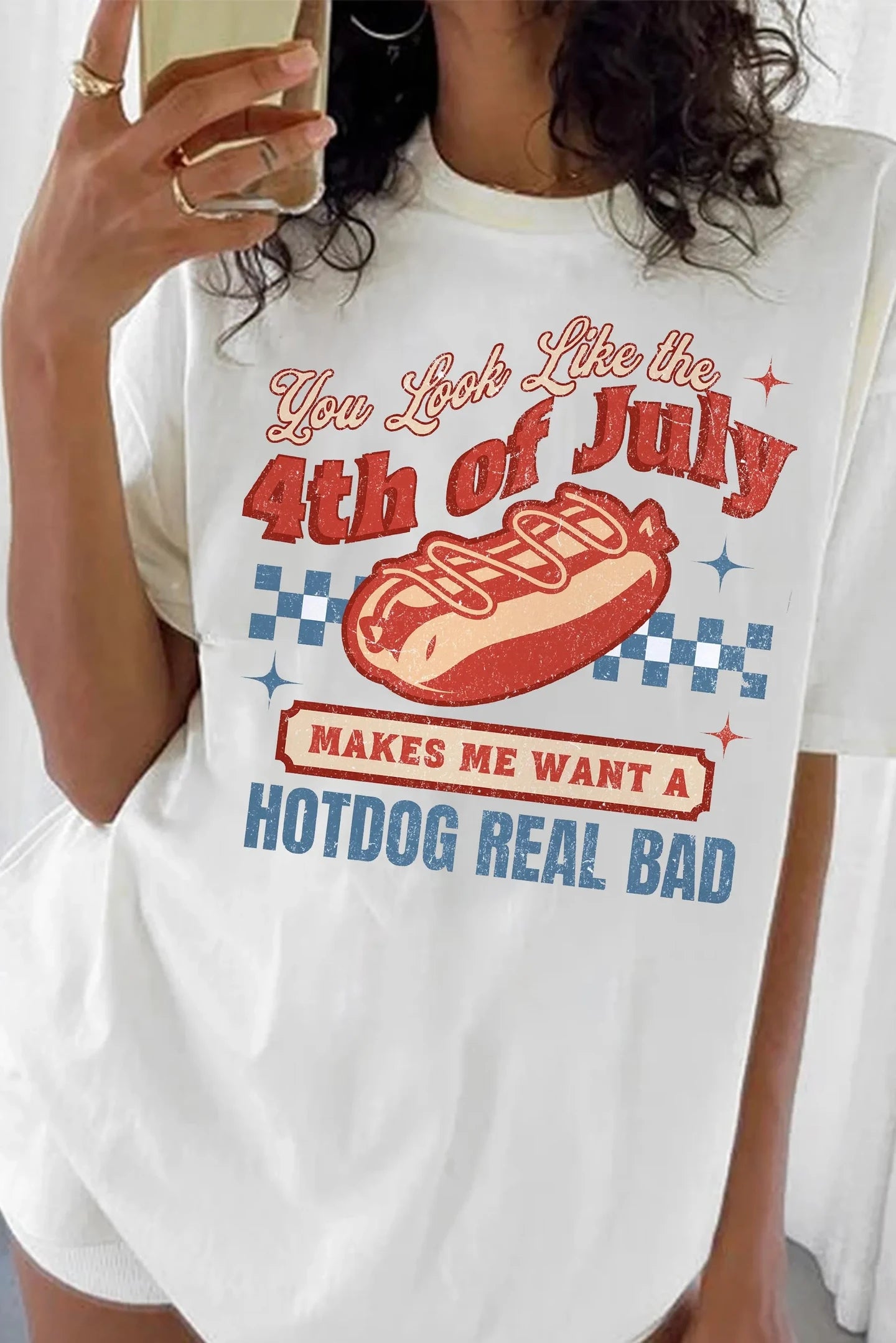 Person wearing a white t-shirt with a 4th of July hotdog graphic and text.